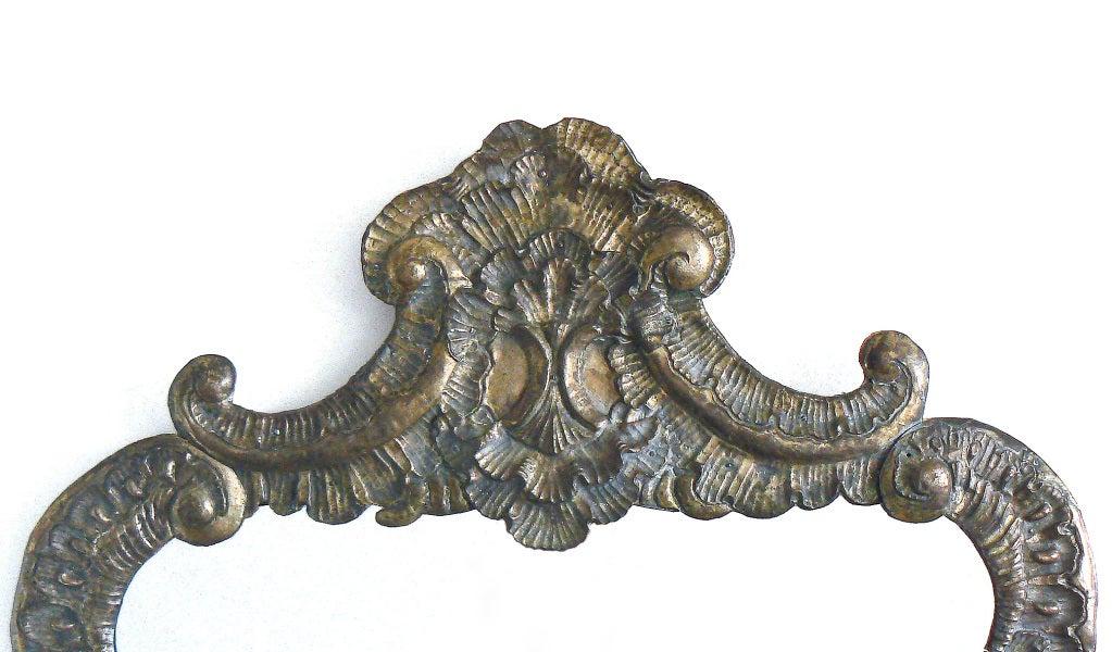 A large and impressive cartouche-form repoussé silvered-brass mirror with shells and C-scrolls and remnants of the original silver surface. Probably Venetian, early 19th century. The noble antique patina has been left untouched.