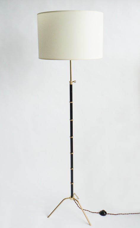 An elegant pair of adjustable height floor lamps by Maison Arlus. Each with bamboo-form design in brass and lacquered wood, on raised brass tripod foot.