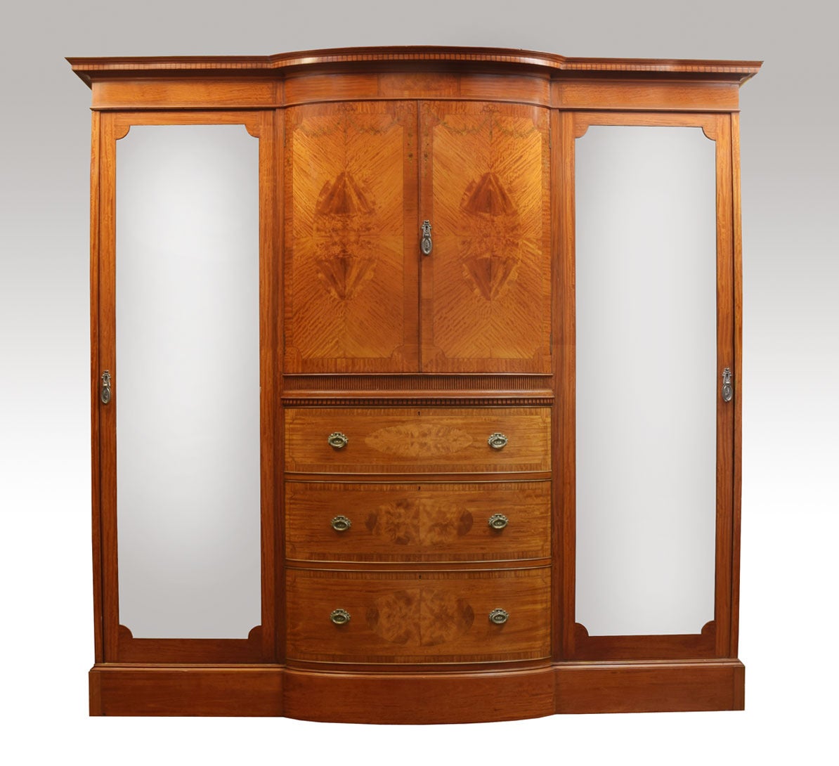 Satinwood inlaid bedroom suit

the bow fronted  wardrobe, having stepped cornice with inlaid freeze to the two bow fronted central doors with painted floral swags opening to reveal large storage area with two fixed shelf over four graduated