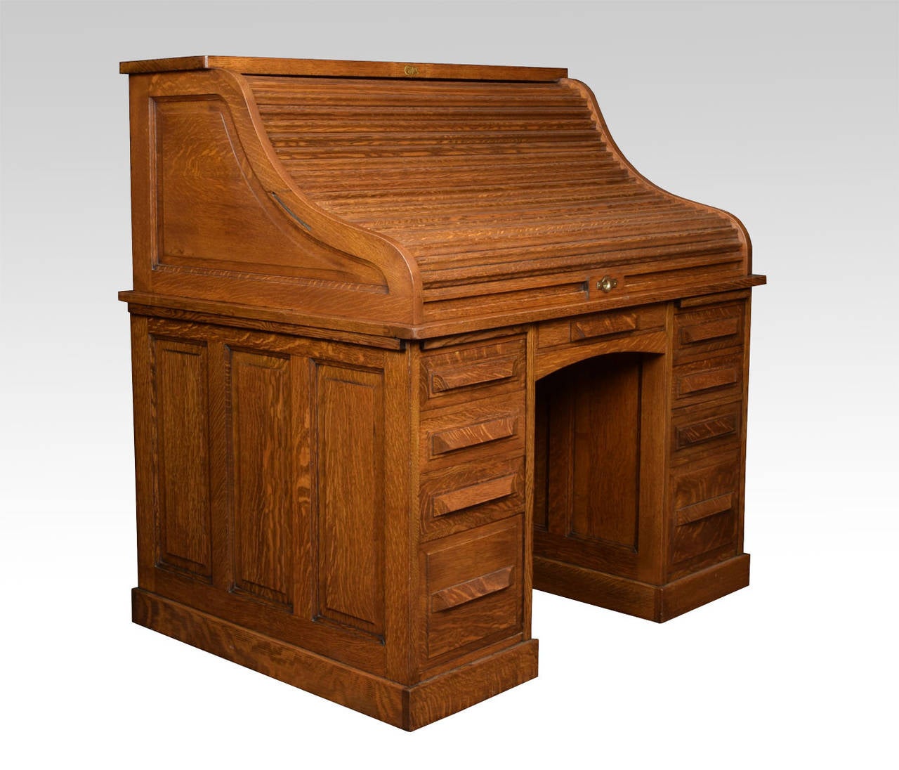 Oak double pedestal roll top desk, the high back with fully fitted interior of pigeon holes and drawers, the centre drawer flanked by pedestals having brush in slide above three short draws and one double draw raise up on plinth base

Abner Cutler