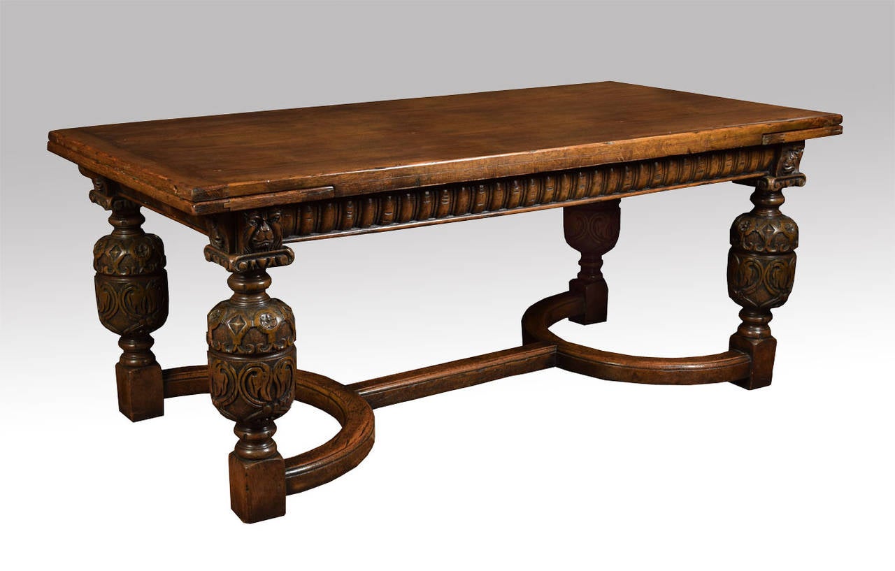 Oak Draw-Leaf Table of generous proportions. The thick plank top having pull-out leaves to each end having strap-work frieze with lion mask carving above the bulbous cup & cover legs leading down to block feet united by