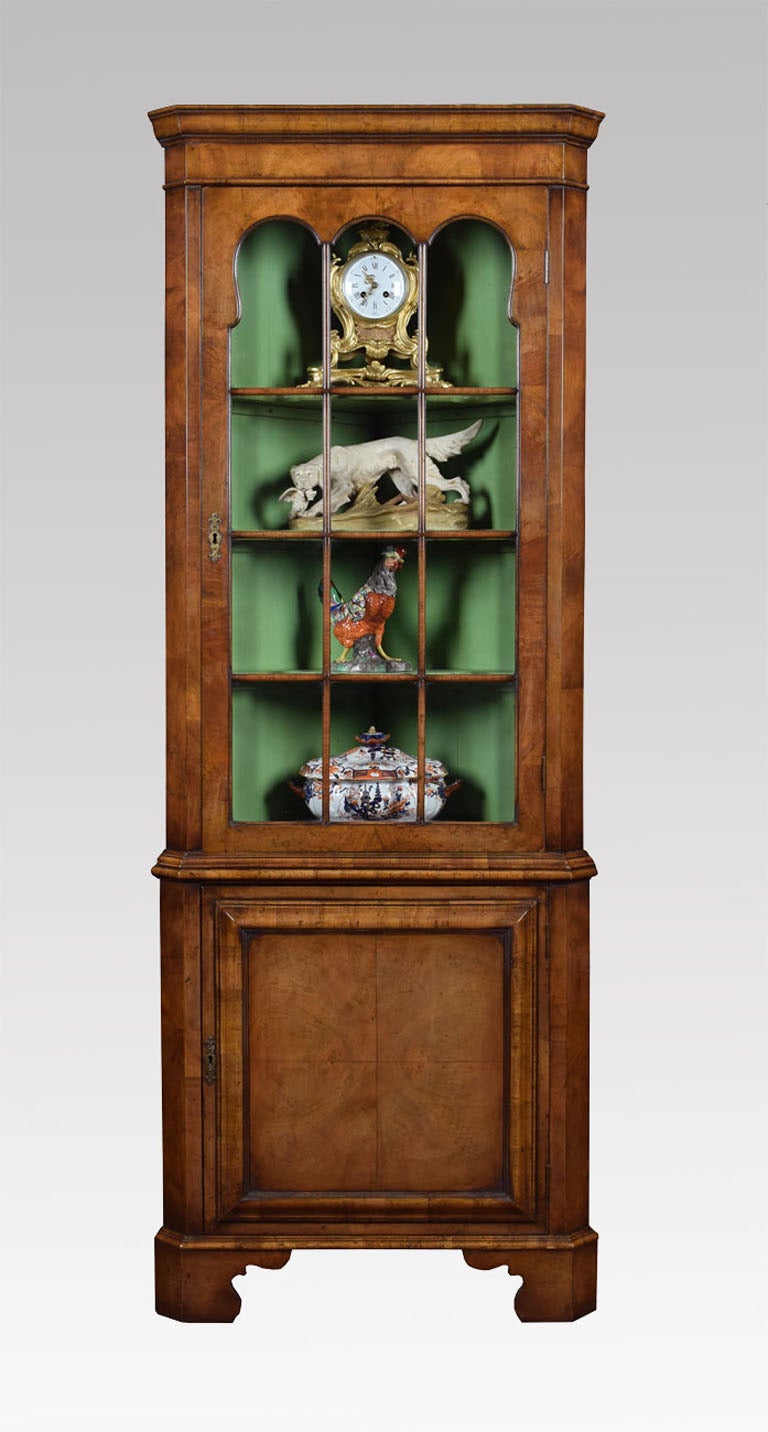 Early 18th century style walnut floor standing corner cabinet, the moulded cornice above single astragal glazed door enclosing three fixed shelves to the base section with a panelled cabinet door opening to reveal single fixed shelf all raised up on