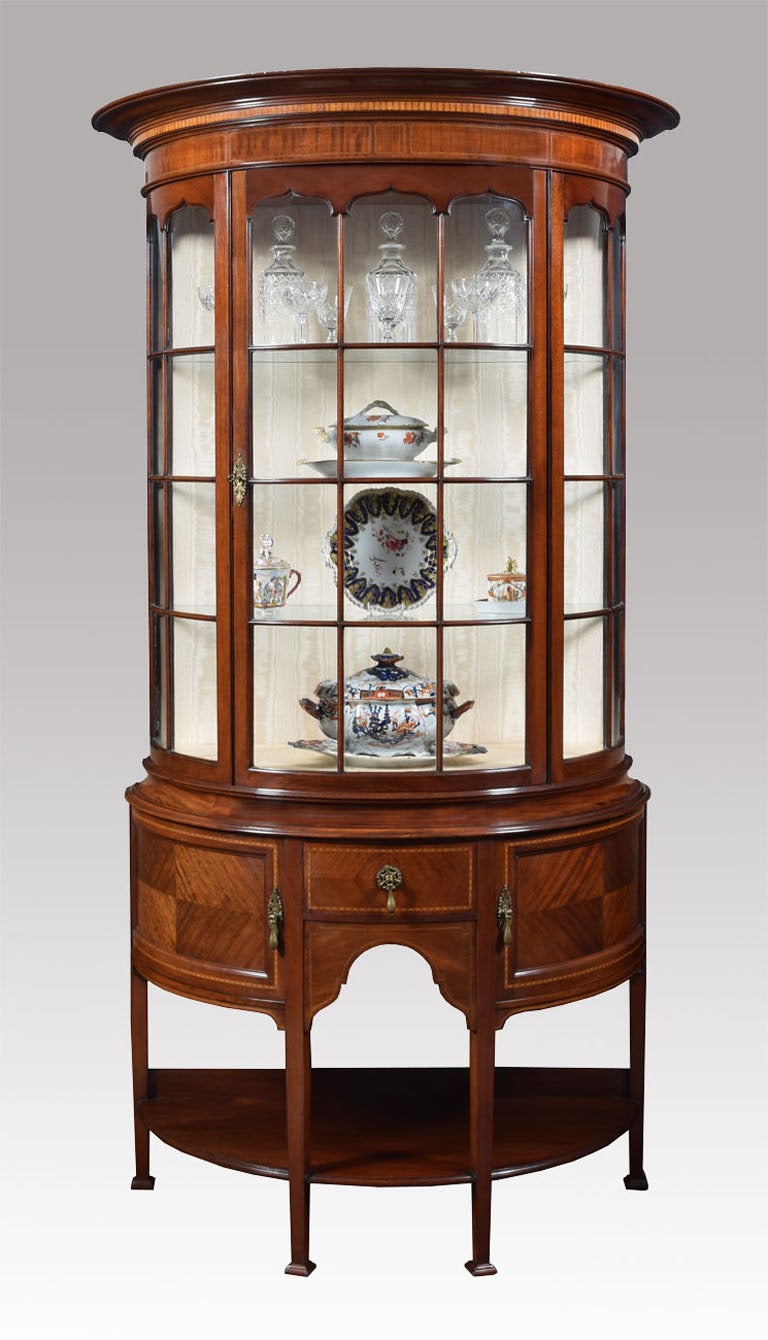 Mahogany Sheraton revival display cabinet the moulded top above single glazed door opening to reveal three glazed shelves, above a central draw having panelled doors to each side with brass drop handles. All raised up on square tapering