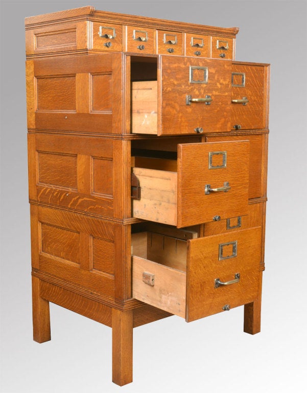 solid oak Shannon filing cabinet the top section having four short draws with brass handles and name panel
The lower section consisting of six oak filing draws all having metal runners raised up on four square legs united by stretcher