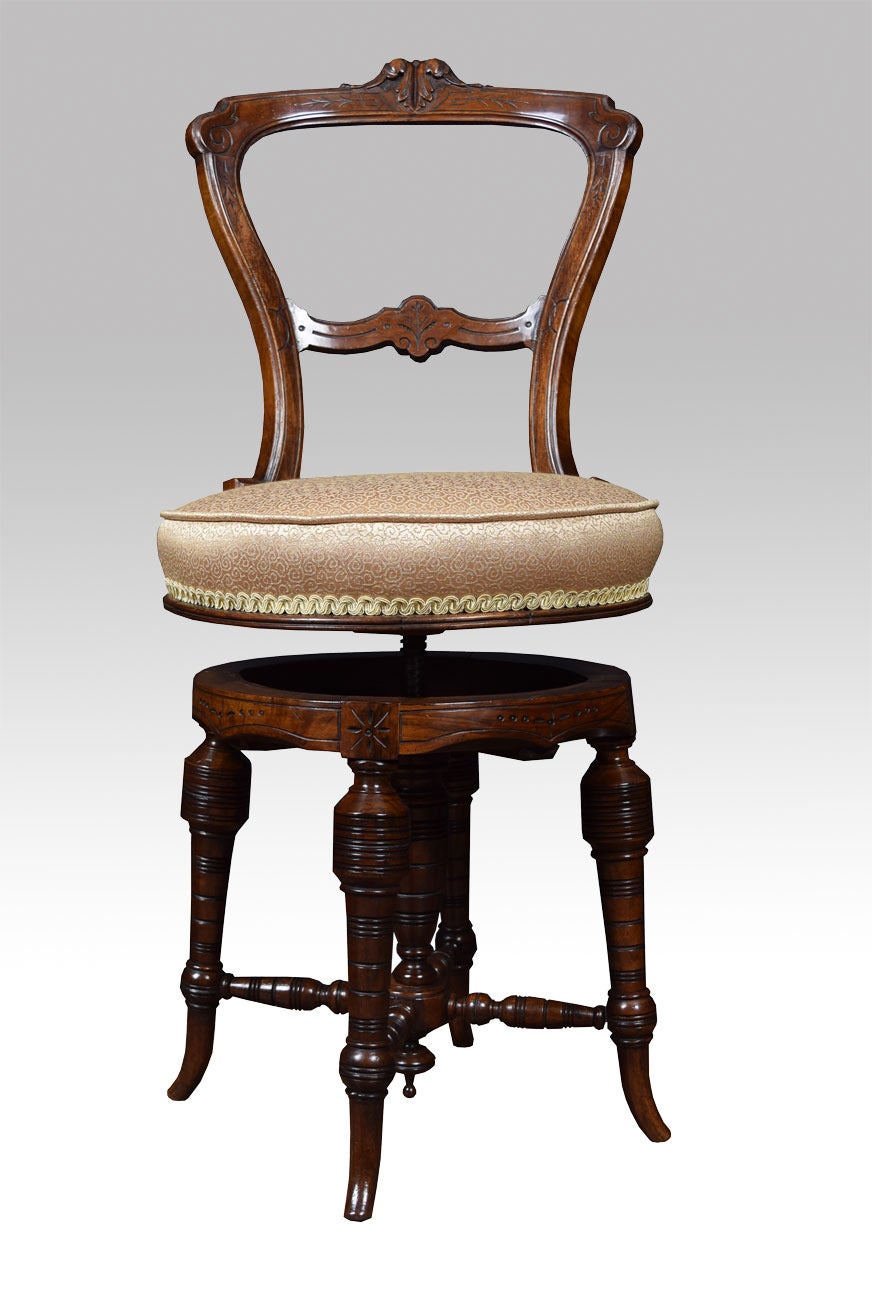 Victorian walnut revolving dressing / music chair, having carved shaped back and with central acanthus scrolls, to the revolving upholstered circular adjustable seat rising above a circular frame with carved and fluted splayed legs united by turned
