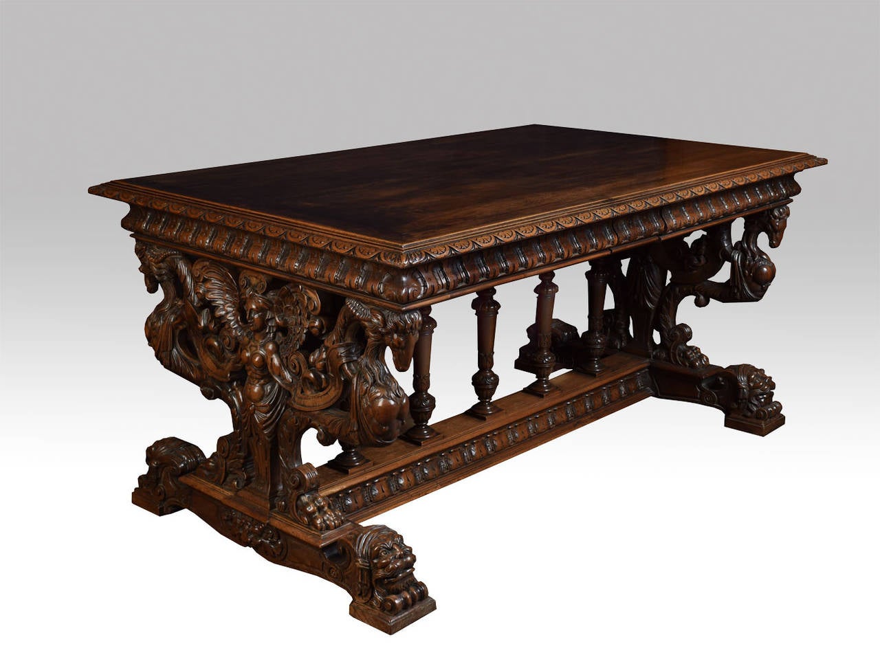 An Italian walnut center table, the rectangular top with carved moulded edge with two freeze draws to either side, on an elaborately carved trestle ends stylised carved figure with chivera, on plinth base with stylised mask headed feet, the ends