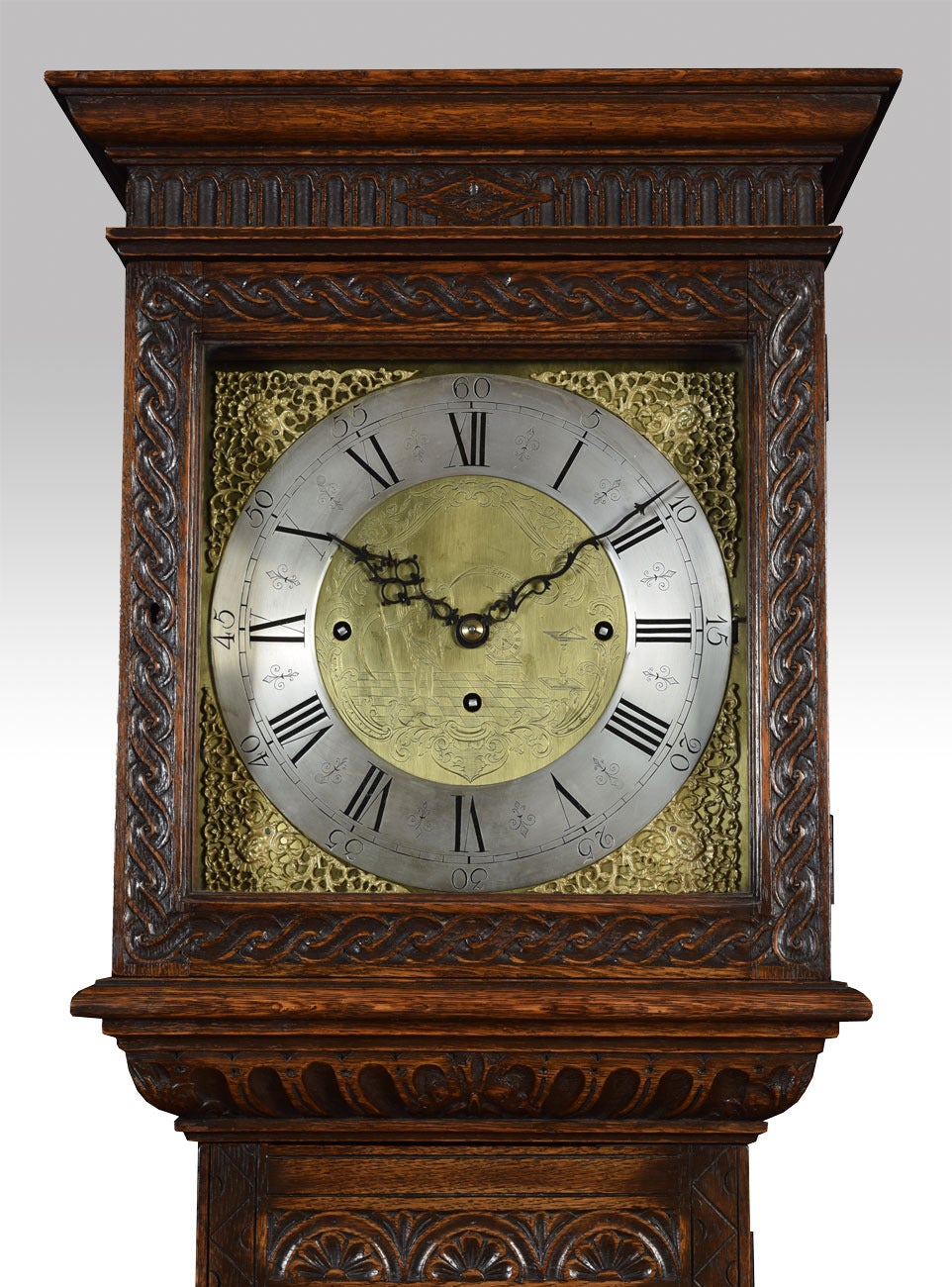 Carved oak longcase clock, the brass and silvered 33cm dial with spandrels, Roman numerals and three winding apertures, three train eight day movement striking the quarters on eight graduated bells and a saucer gong, the carved case having flat top
