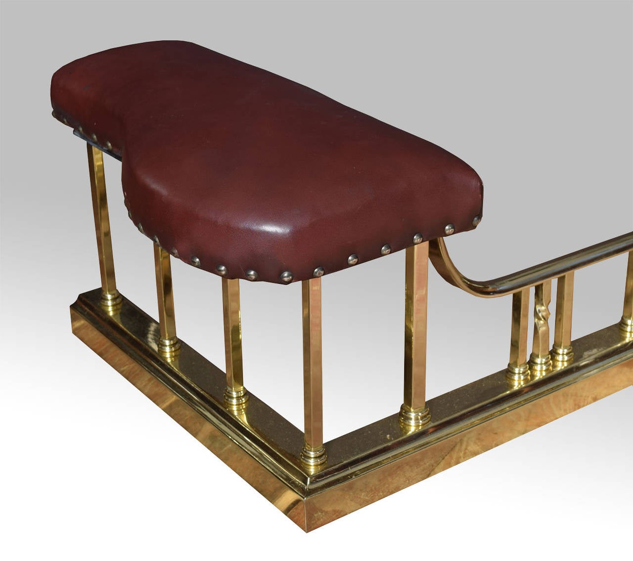 early 20th Century brass club fender, with two seat pads upholstered in dark red leather on decorative square and spiral twist supports.

Height 12.5 Inches

Internal measurements

Length 67 Inches

Depth 16 Inches

 External