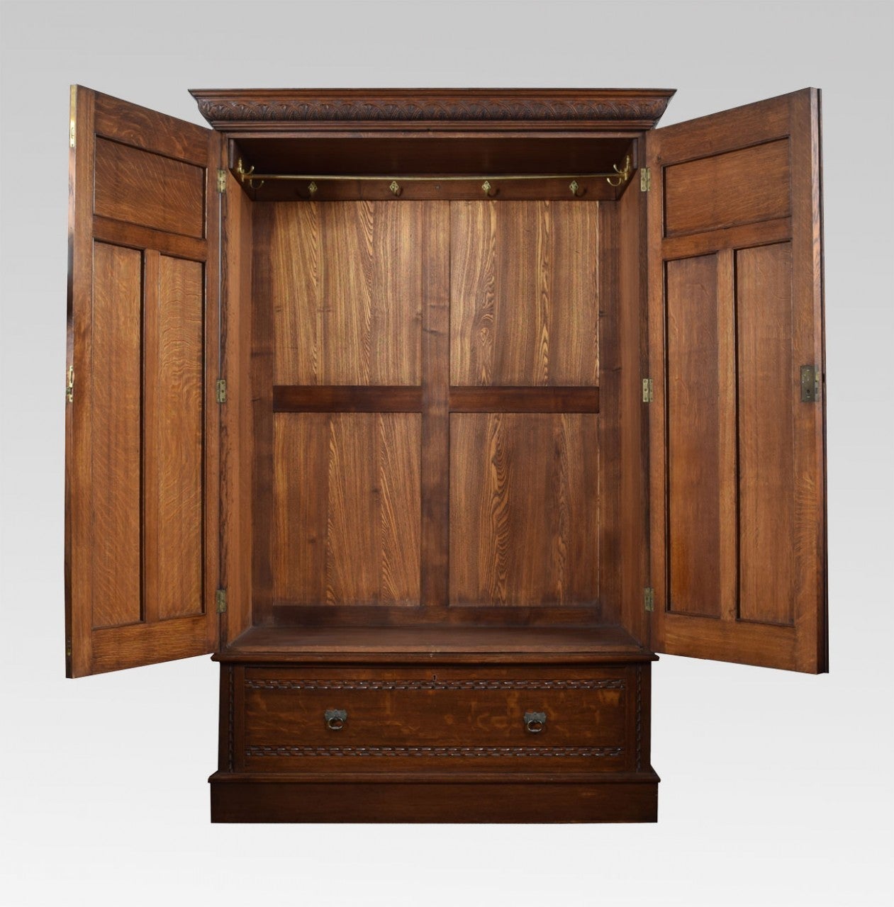 Oak two door wardrobe the acanthus carved cornice above two large oak panelled doors opening to reveal large hanging area the base fitted with single draw having brass tooled  handles  all raised up on plinth base

Dimensions: Height 79