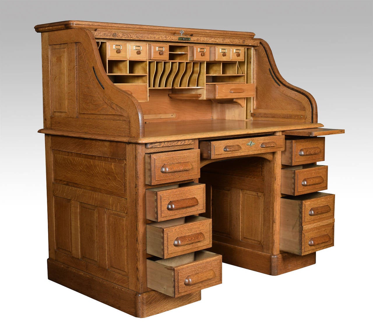 Oak double pedestal roll top desk, the high back with fitted interior of pigeon holes and drawers, the centre drawer flanked by pedestals one with four short draws the other with two short and one double draws raise up on plinth base

Height 50