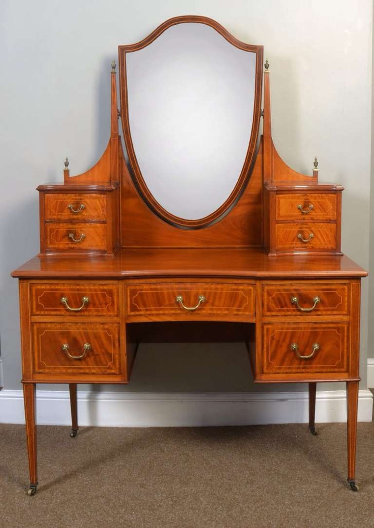 Edwardian Mahogany dressing table, the shield shaped mirror flanked by two short drawers to each side above figured mahogany top. The base section fitted with central draw having brass swan neck handles with two further draws to either side all