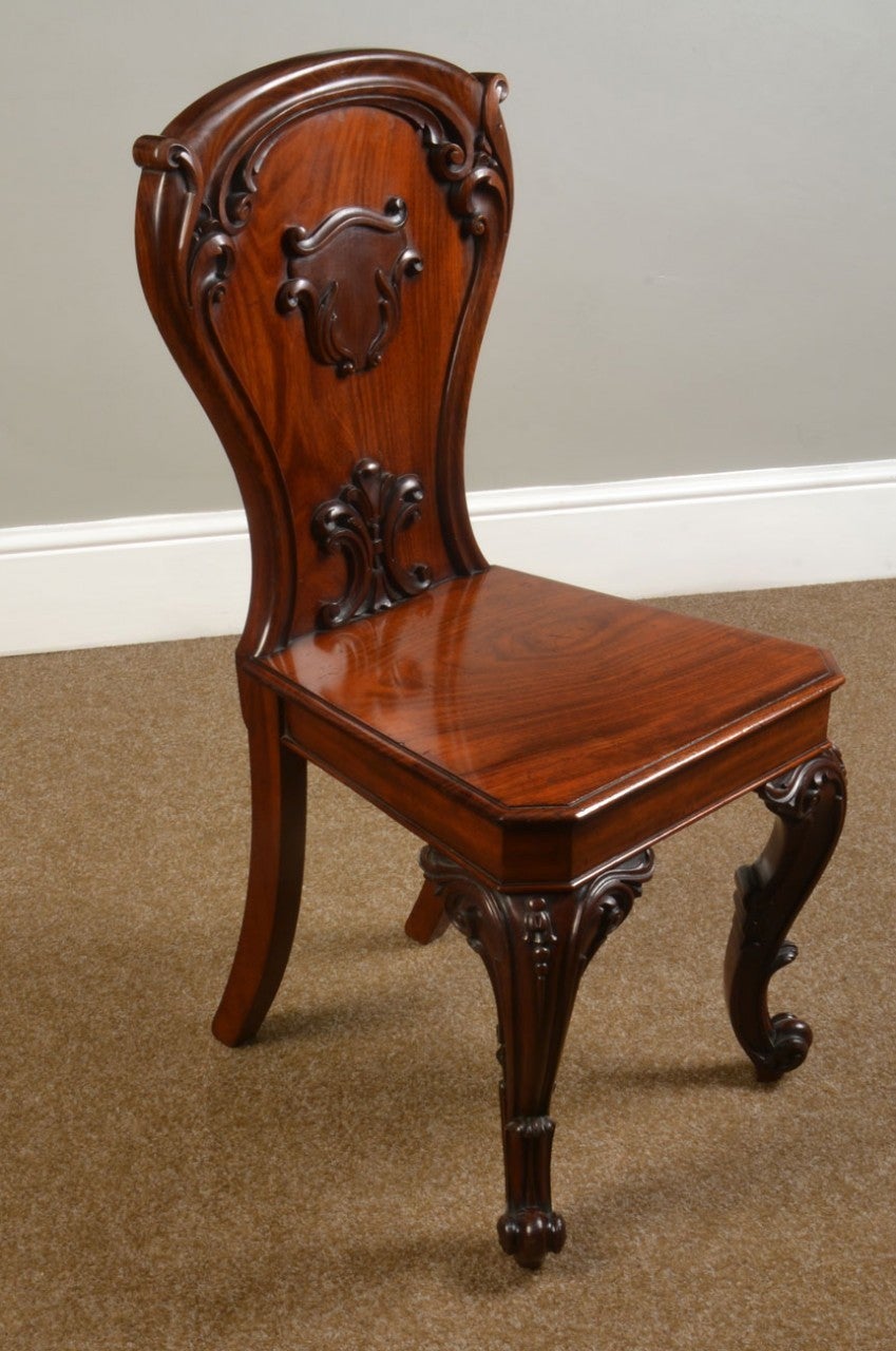 Pair of Victorian mahogany hall chairs the shaped backs having central carved motif with further foliated carving to the edge the solid mahogany seat raised up on cared cabriole scrolling front legs

Dimensions:

Height 36 inches height to seat