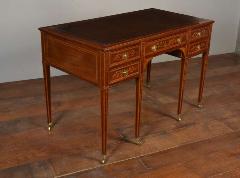 Late Victorian mahogany, satinwood banded and marquetry desk The top with replaced brown leather writing surface, above five drawers, the central drawer stamped 