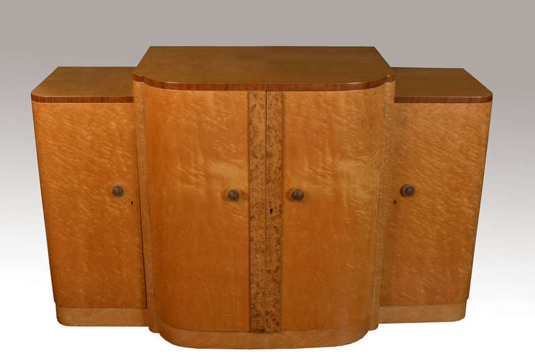 Art deco four door sideboard having large maple top with rounded corners, above a pair of central doors with circular tooled handles opening to reveal three long draws and wine holder below, flanked by two further doors opening to reveal two fixed
