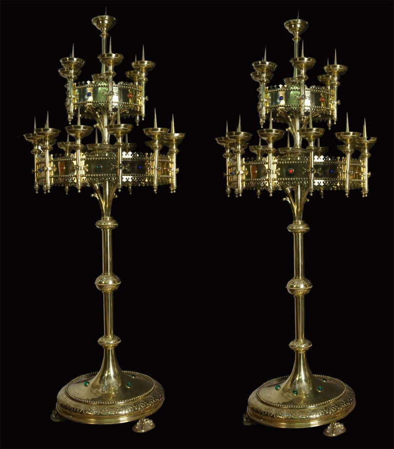 Large pair of Victorian gothic floor-standing candelabras, each with two rings supported by foliate brass branches and applied with coloured glass cabachons supporting twenty candle holders raised up on paw feet inscribed D.D Maria Lepeugque Anno