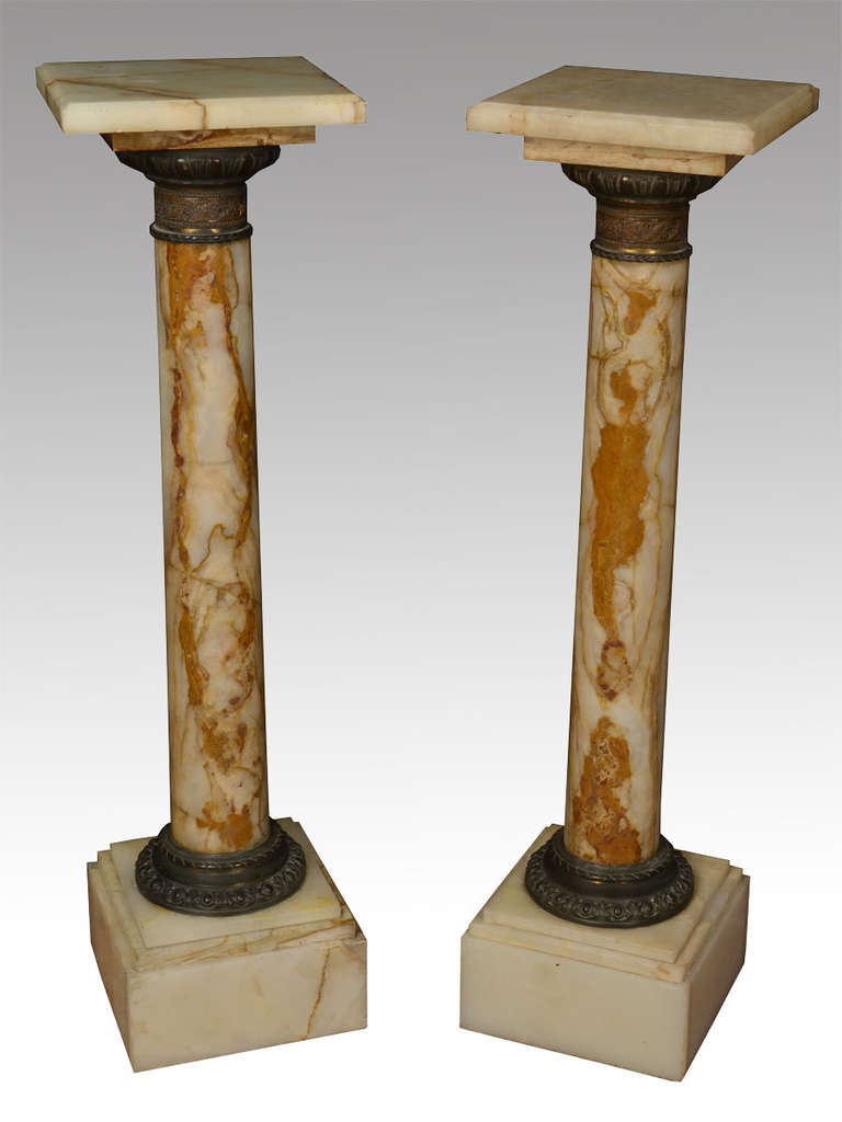 Pair of onyx Marble and Gilt Metal Mounted Pedestals, with square revolving platforms above scrolling leaf cast socles and column supports, raised on stepped platform bases