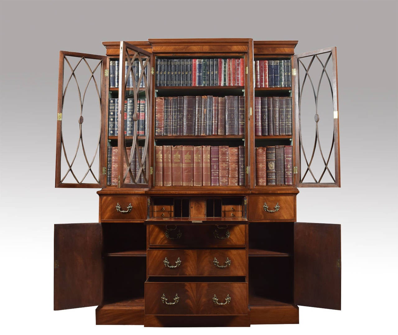 Mahogany breakefront bookcase the top section with moulded cornice above four astragal-glazed doors enclosing adjustable shelves, the lower section with secrétaire drawer with fall front enclosing a yew-veneered interior of short drawers and
