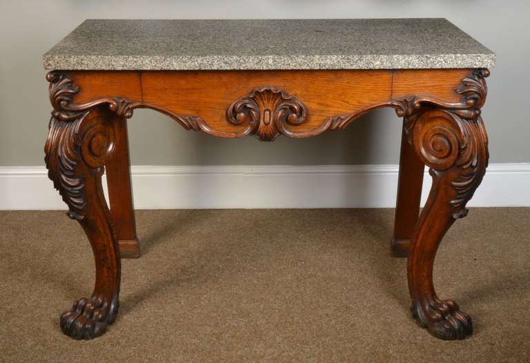 19th century probably Irish carved oak side table with green rectangular marble-top above the shaped frieze fitted with single central drawer flanked by overtly bold scroll and acanthus carved cabriole supports terminating on hairy paw feet.