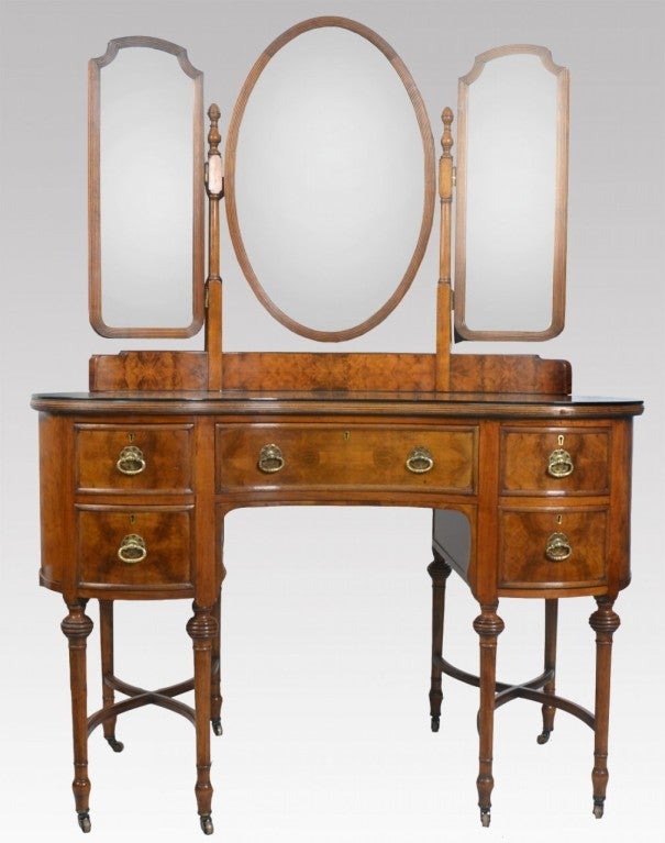 Walnut kidney shaped dressing table having an ornate superstructure with central oval mirror and rectangular mirror to either side. The base with glazed top above one large central draw flanked by two short draws to each side raised up on eight