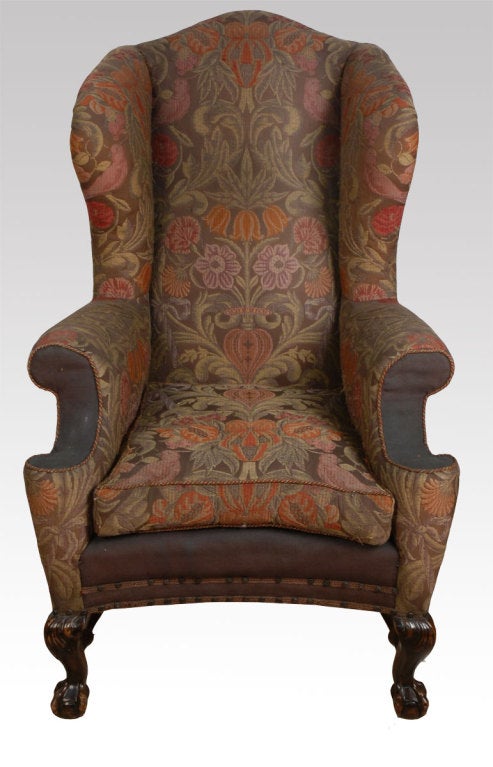Pair of Large Early Georgian-Style Wing Chairs, upholstered in brown needlepoint upholstery overlaid with floral embroidery and multicoloured fringes, With a shaped back, wings and outs crolled arms flanking a bowed loose cushion seat, on carved