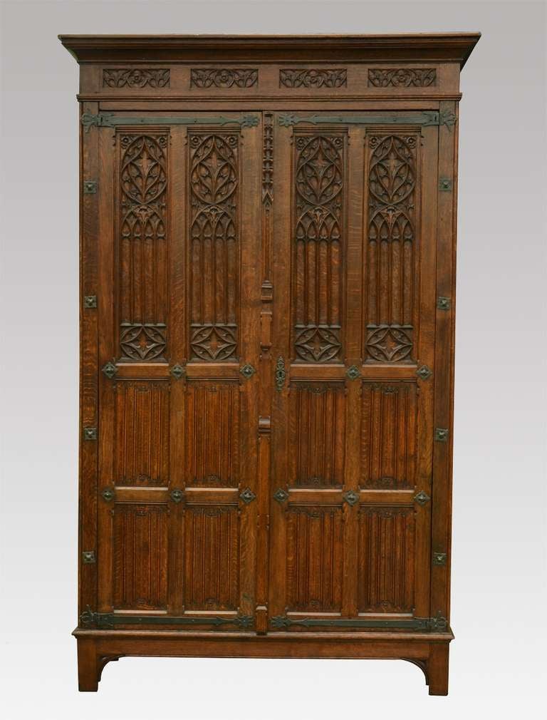 Gothic revival oak wardrobe the projecting cornice above two large  paneled doors having Gothic carving throughout and wrought iron mounts the two doors opening to reveal large storage area raised up on bracket

Dimensions

Height 89