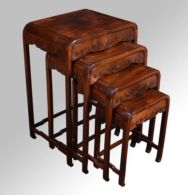 nest of four Chinese rosewood tables each with a recessed panel to the rectangular top and a carved frieze on four slender supports with conforming stretchers