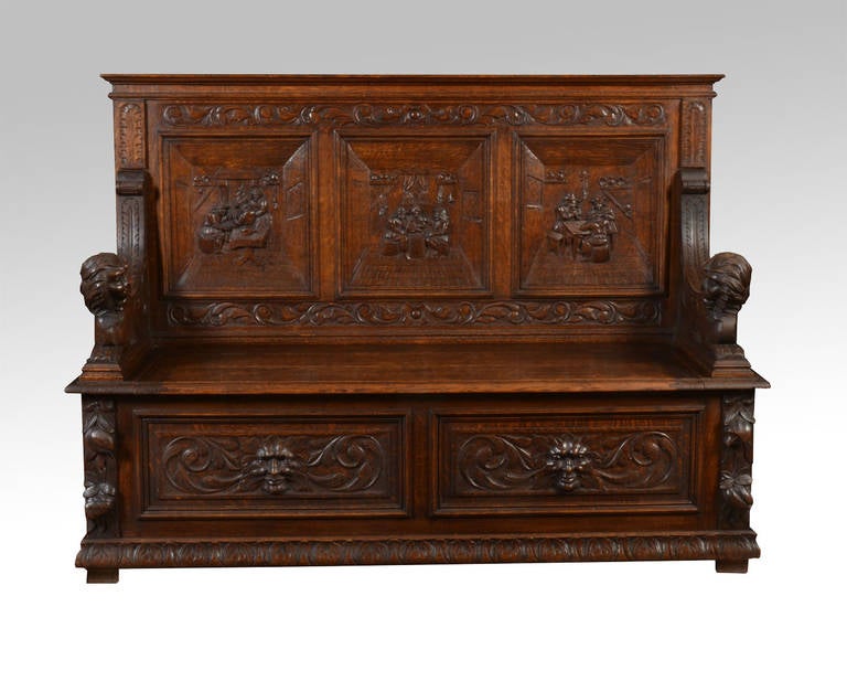 19th Century carved oak hall settle with three panelled  tavern scenes back above carved lion arm rests to the lift up seat the base with two green man carved panels raised up on bracket feet

Dimensions

Height 44 Inches Height to seat 17.5