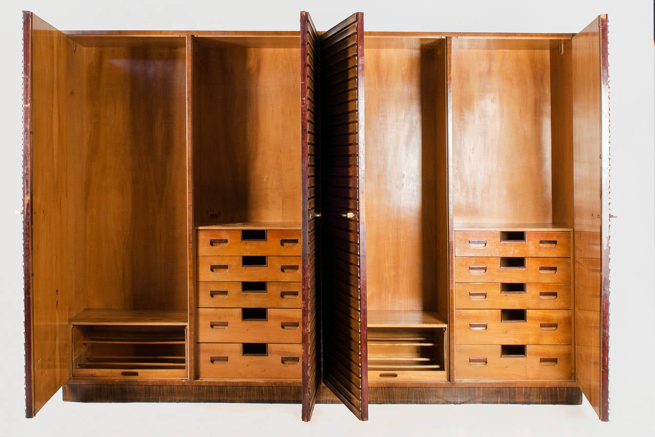 Extraordinary armoire, created in the 1930s, Italy. Four doors with two series of drawers, internal mirror. Structure and handles in walnut with brass elements.