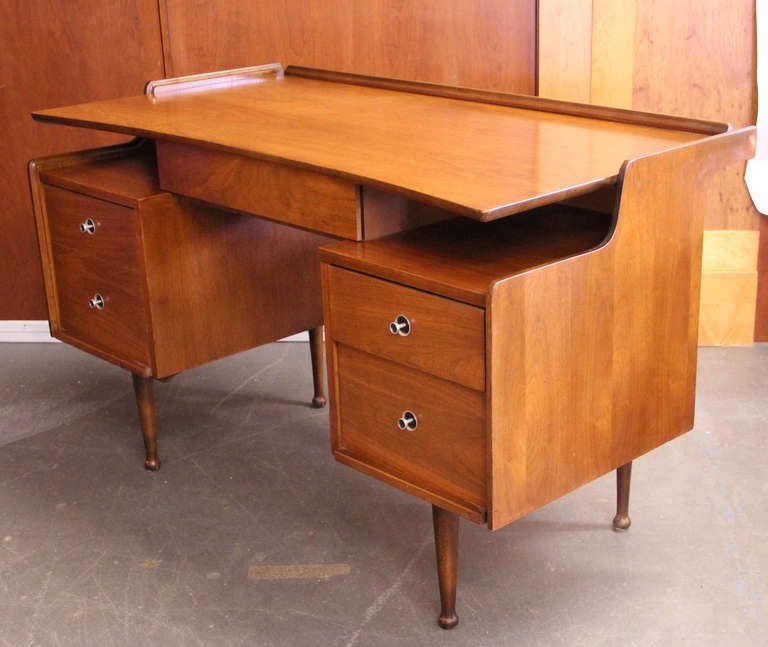 Vintage mid-century modern walnut desk with floating top design, four side drawers and center lap drawer.
