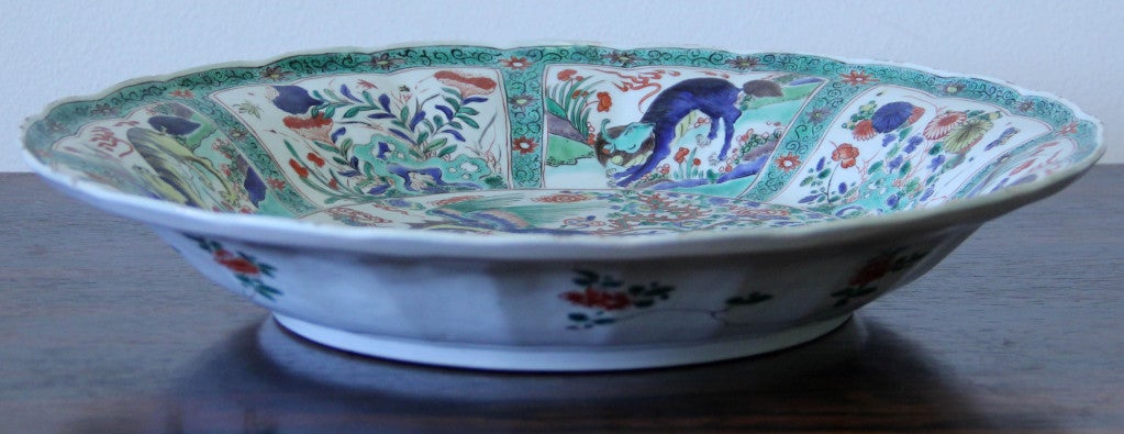 A fine porcelain charger with alternating cartouches of floral decoration and mythical beasts. The center decorated with a mythical beast and bird in a landscape. Kangxi period (1662-1722), China.