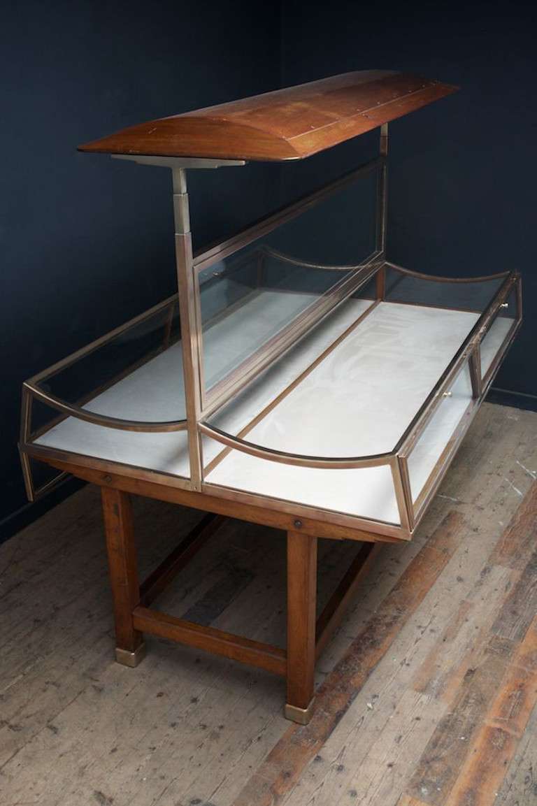 We have three of these superb bronze and oak retail display units.
Oak base with bronze feet and a mahogany canopy ,the glazed frame has two large curved glass display panels to the top, four doors to the sides with original working locks and keys,