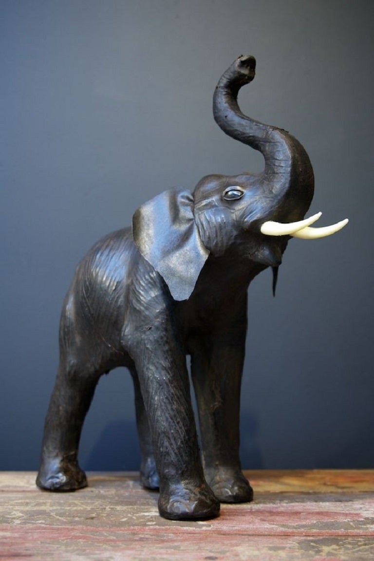 A vintage brown leather fireside Elephant with trunk raised. 

Glass eyes, wonderful patina. 

1950s. 

H:54 W:20 D: 54 CM