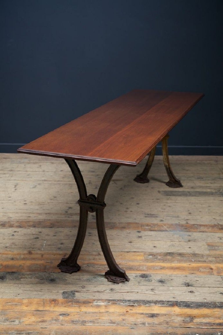 A cast iron and mahogany trestle Pub Table. 

Remnants of old paint to the cast base. 

English mid-19th century.