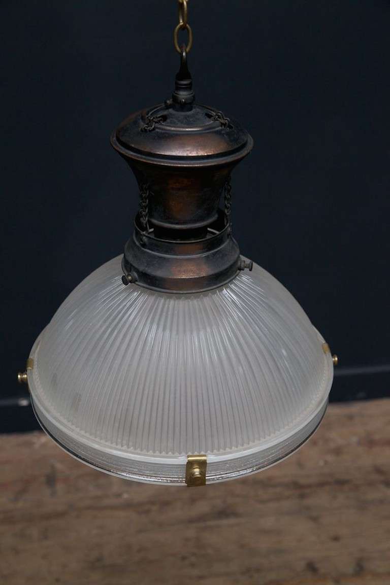 A Prismatic Holopane pendant light with a unusual two part gallerie with chains linking the two parts, original bronzed finish to the copper.
English 1920s.
Rewired and pat tested.
Another similar but smaller pendant available see ref