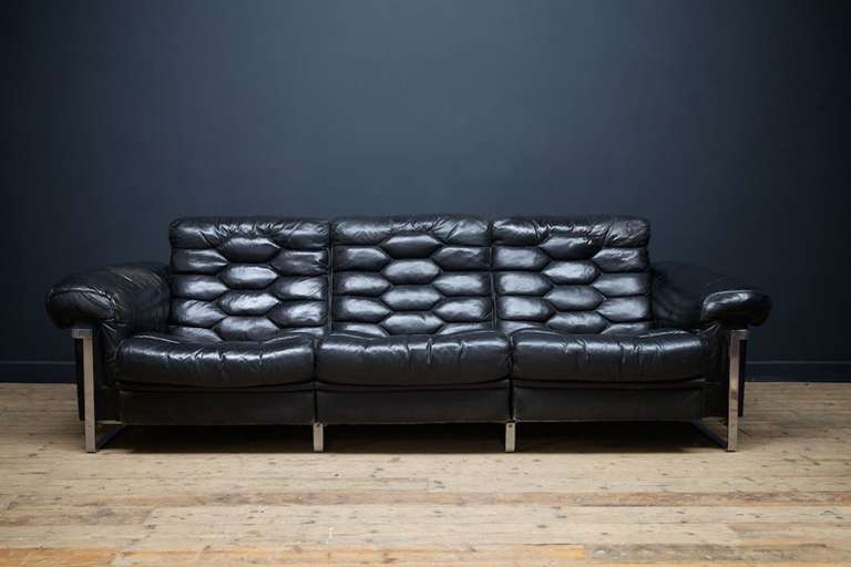 A black leather three seater sofa.
Manufactured by Swiss furniture company De Sede and designed by Robert Haussmann in the 1960s.
The solid hardwood frame with steel frame mounted on sliders.All three seat section pulls out by approximately 10cm