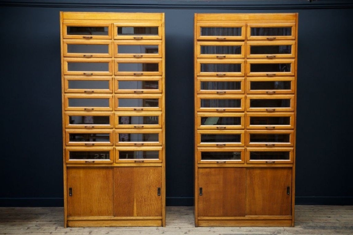 A run of five oak haberdashers retail display cabinets. 

Sixteen glass fronted dawers above a pair of sliding doors. 

Extremley clean condition and all are identical. 

English 1930s. 

Five available, price is per cabinet. 

H:199 w:94