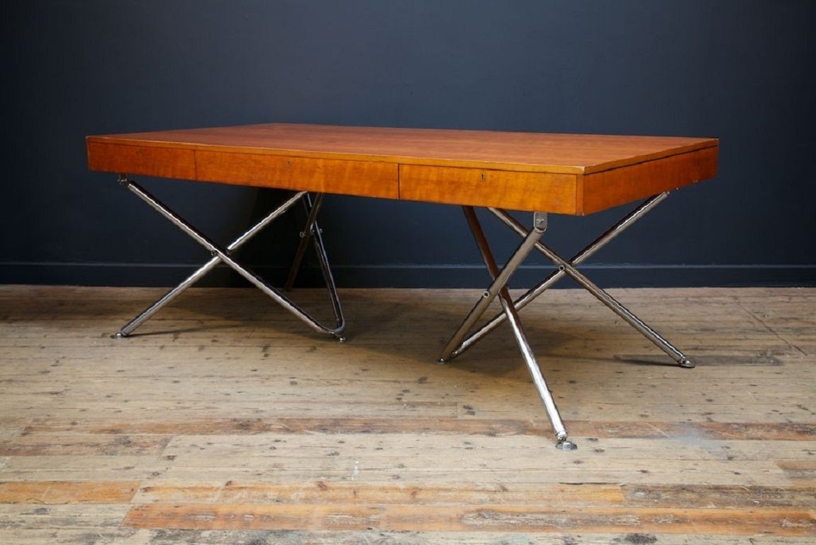 Exceptional post war modernist desk. 

Fruitwood veneer over ply frame supported by tubular chromed scissor action supports. 

The frieze has three full width and depth drawers. 

Makers label to central drawer lining “Andrew Thomson & Son,