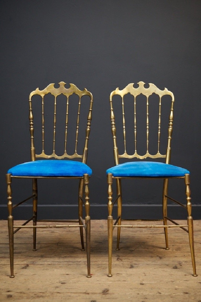 A pair of brass chairs designed by Giuseppe Gaetano Descalzi. 

This chair has been produced from the early 19 th century, this pair date to the second quarter of the 20th century. 

Faded blue velvet upholstery, older repair to the side