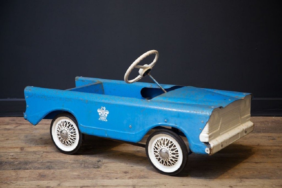 A Bermuda Triang pedal car. 

Original paint with Prince of Wales feathers sign writing. 

1950s. 

H: 42 W: 85 D: 37 CM