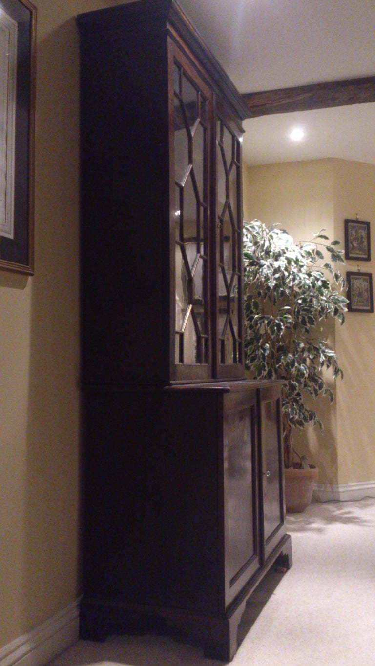 Oak bookcase of unusually small proportions, glazed above with cupboards underneath. It has thin glazing bars and delicate molding typical of the late Georgian period, English, circa 1800.

   