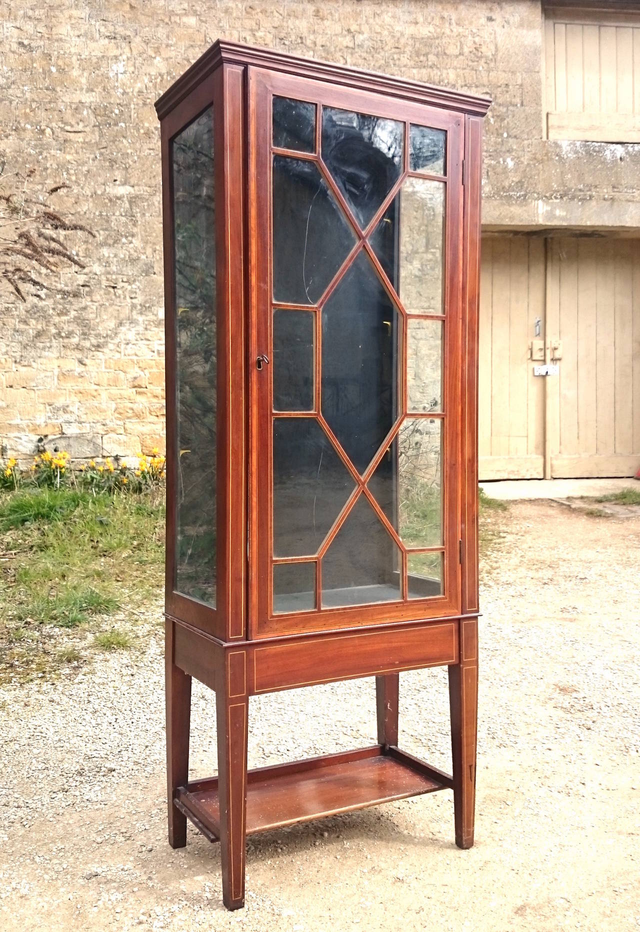 Antique cabinet with three glass shelves, working lock and key. It is made of mahogany with boxwood stringing and inlay. This is a wonderful quality and useful cabinet with only a few marks commensurate with the age of the piece. The glass shelves