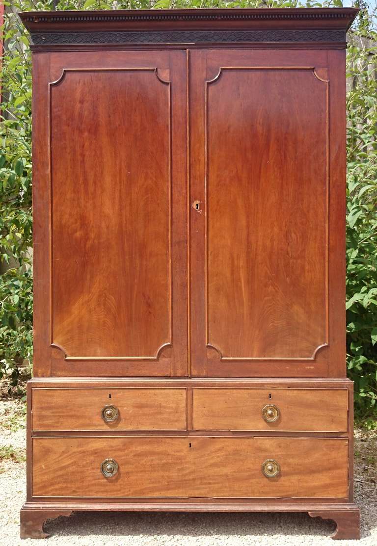 Antique mahogany wardrobe with two doors over drawers. It is made of good timber with symmetrically panelled wood on the doors. The cornice has delicate pierced lattice work, it has good dovetails and has been adjusted to allow for full length
