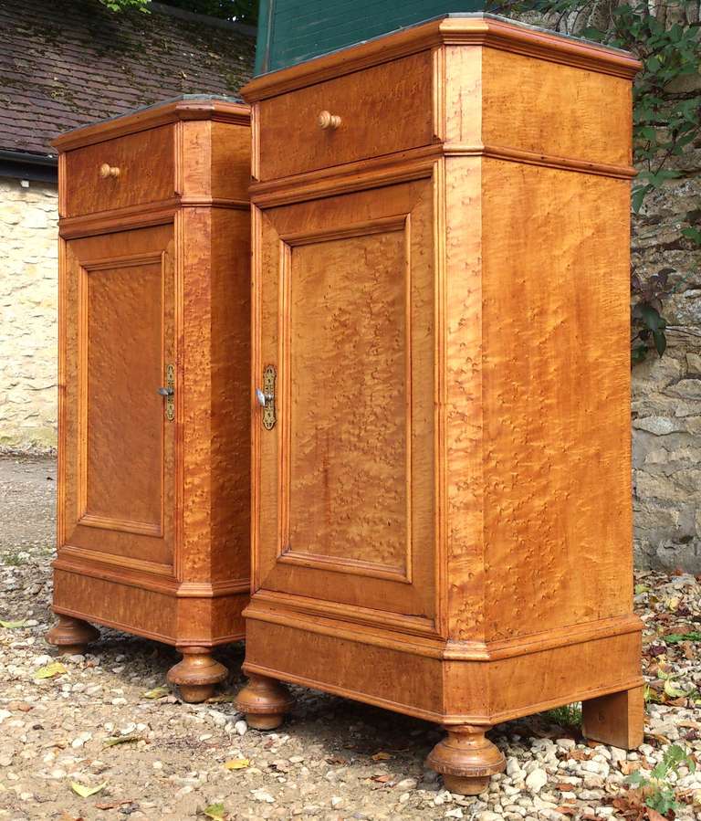 Pair of antique bedside cupboards with marble tops. The timber is 'Birds Eye' maple, an expensive cut of veneer which has a three dimensional quality when it catches the light. The marble tops are a useful feature as they do not get ring marks when