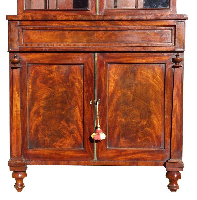 Good early nineteenth century antique bookcase / china cabinet / drinks cabinet made of mahogany with flame mahogany panels, adjustable shelves, drinks drawer and glazed top. English circa 1830 

17″ deep 
35 1/2″ wide 
81″ high max