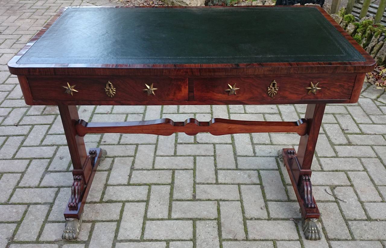Antique writing table or antique library table with leather writing surface. This table represents the Regency period very well with stylistic motifs typical of the period. We like the gilt brass (ormulu) mounts for the feet, handles and