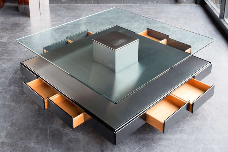 Model T147 designed by Osvaldo Borsani in 1970.

The cantilevered black wood base has unidirectional casters, two drawers per side, a stainless steel top surface and a central square pedestal which supports the 1/2