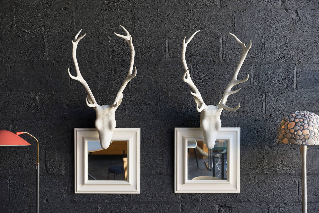 Cast head mounts on wood frame mirrors with painted surface.

Possibly real antlers under white surface.