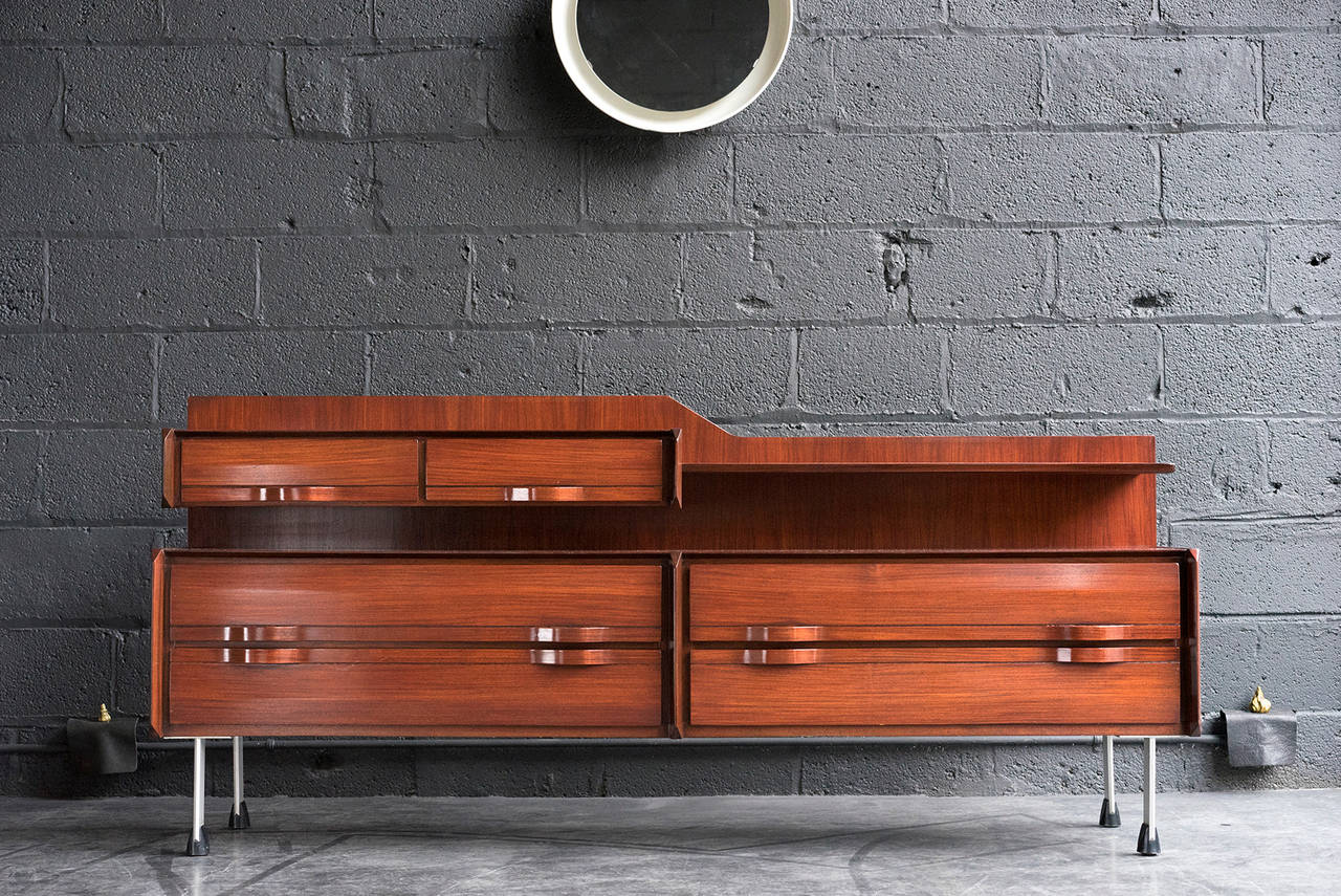 Lovely wood construction with rich tone and grain. Sinuous bentwood ribbon drawer pulls. Two smaller cantilevered drawers and one shelf float over four larger drawers. Raised on metal legs with original, contrasting black feet. Handsome, low
