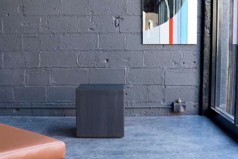 heavy welded steel cube with brushed graphite/gunmetal finish floating on recessed 1/2