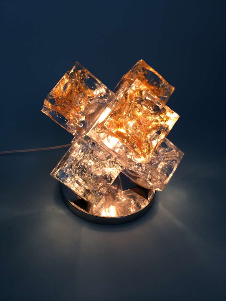 The light includes six unrefined glass cube components with a hemispheric groove in the center and a chromium plated steel base.